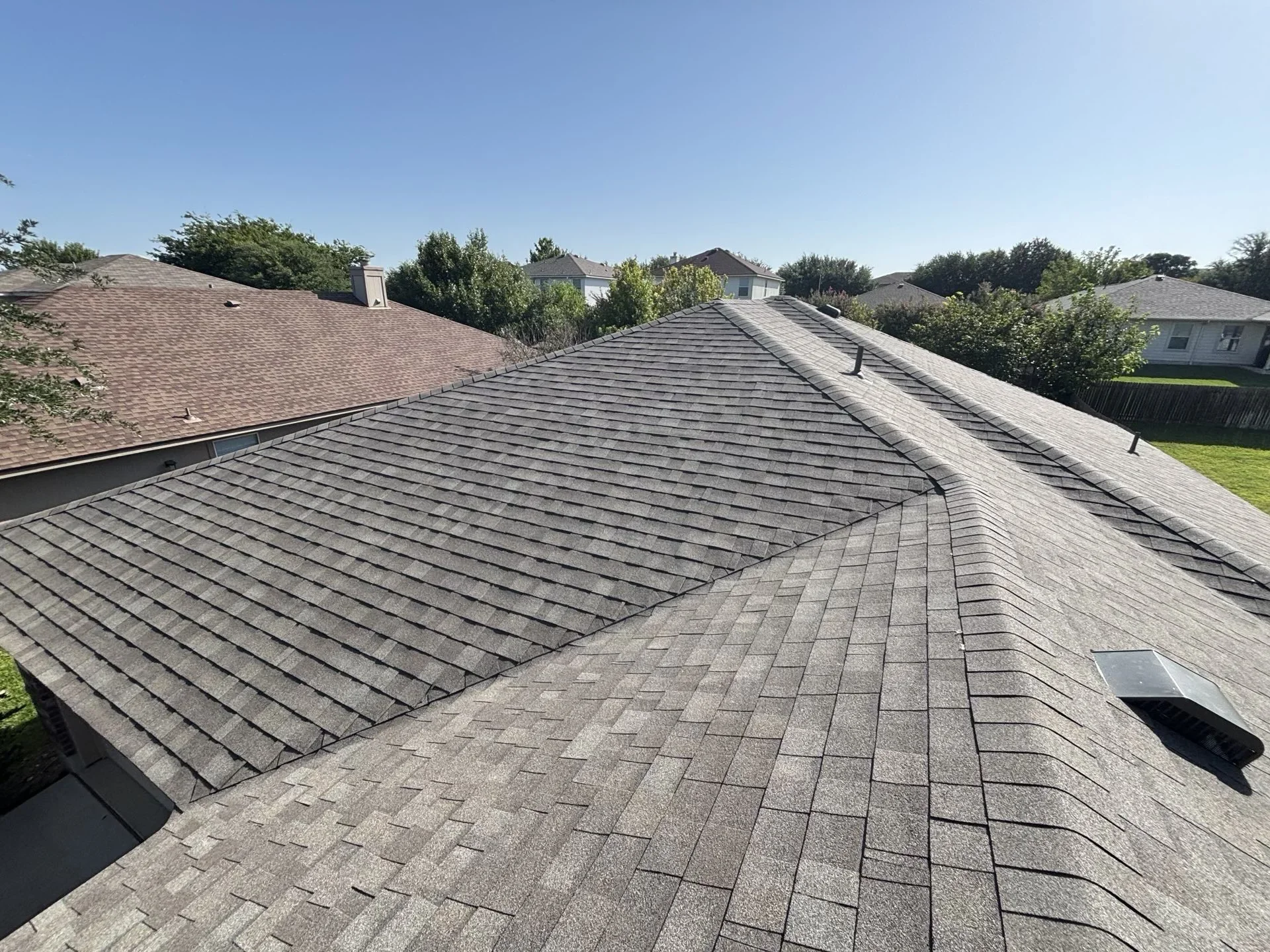 Charcoal gray asphalt shingle roof installation with multiple planes and proper flashing details
