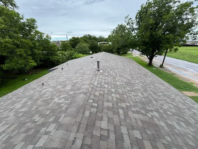 Gray architectural shingles installed in staggered pattern on pitched residential roof with roof vents