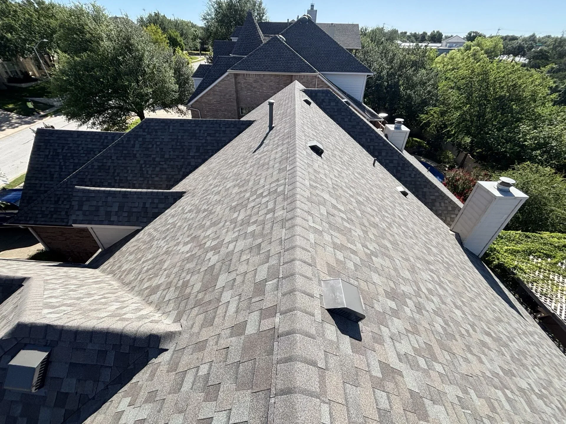 Gray architectural asphalt shingle roof with multiple planes and valleys on residential home