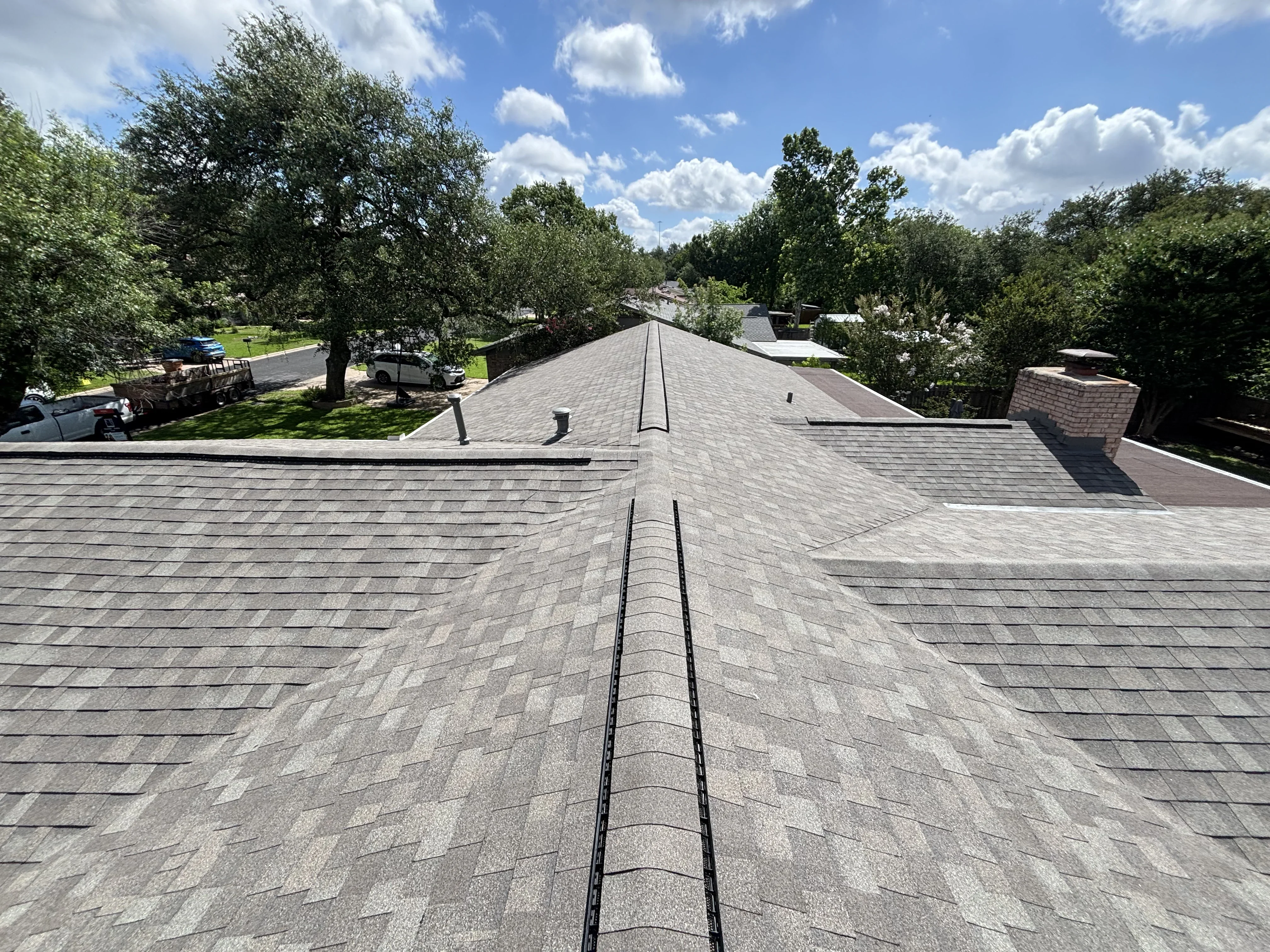 Gray asphalt shingle roof with multiple planes, valleys, and ridge caps on residential home