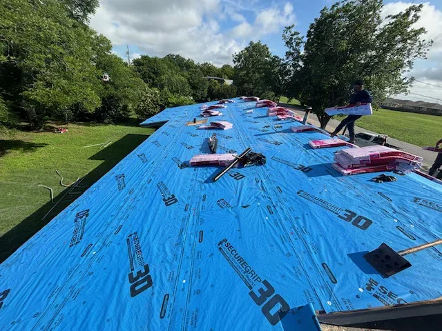 Blue synthetic roofing underlayment installed on residential roof deck with fasteners and sealing tape
