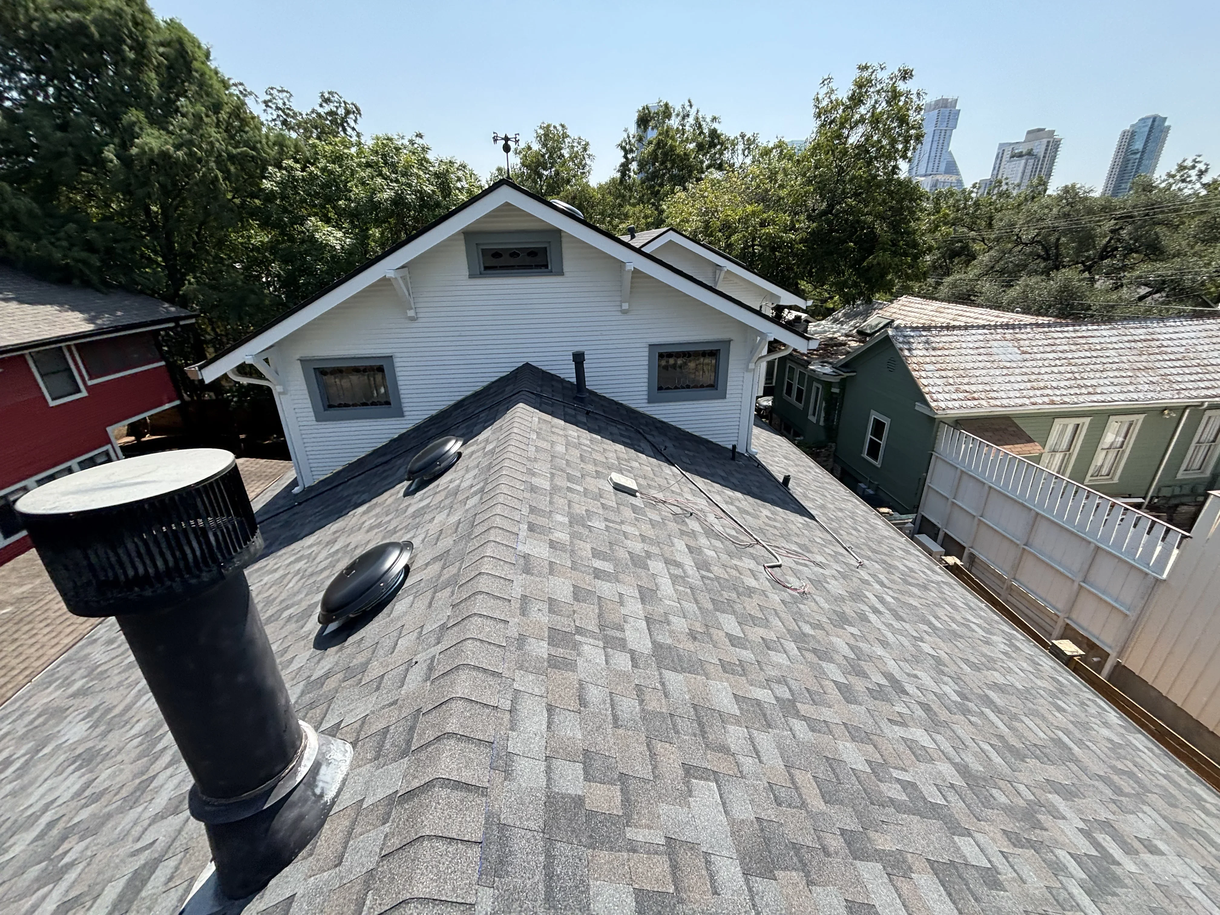 Newly installed gray architectural shingles with herringbone pattern, black roof vent, and flashing on residential roof