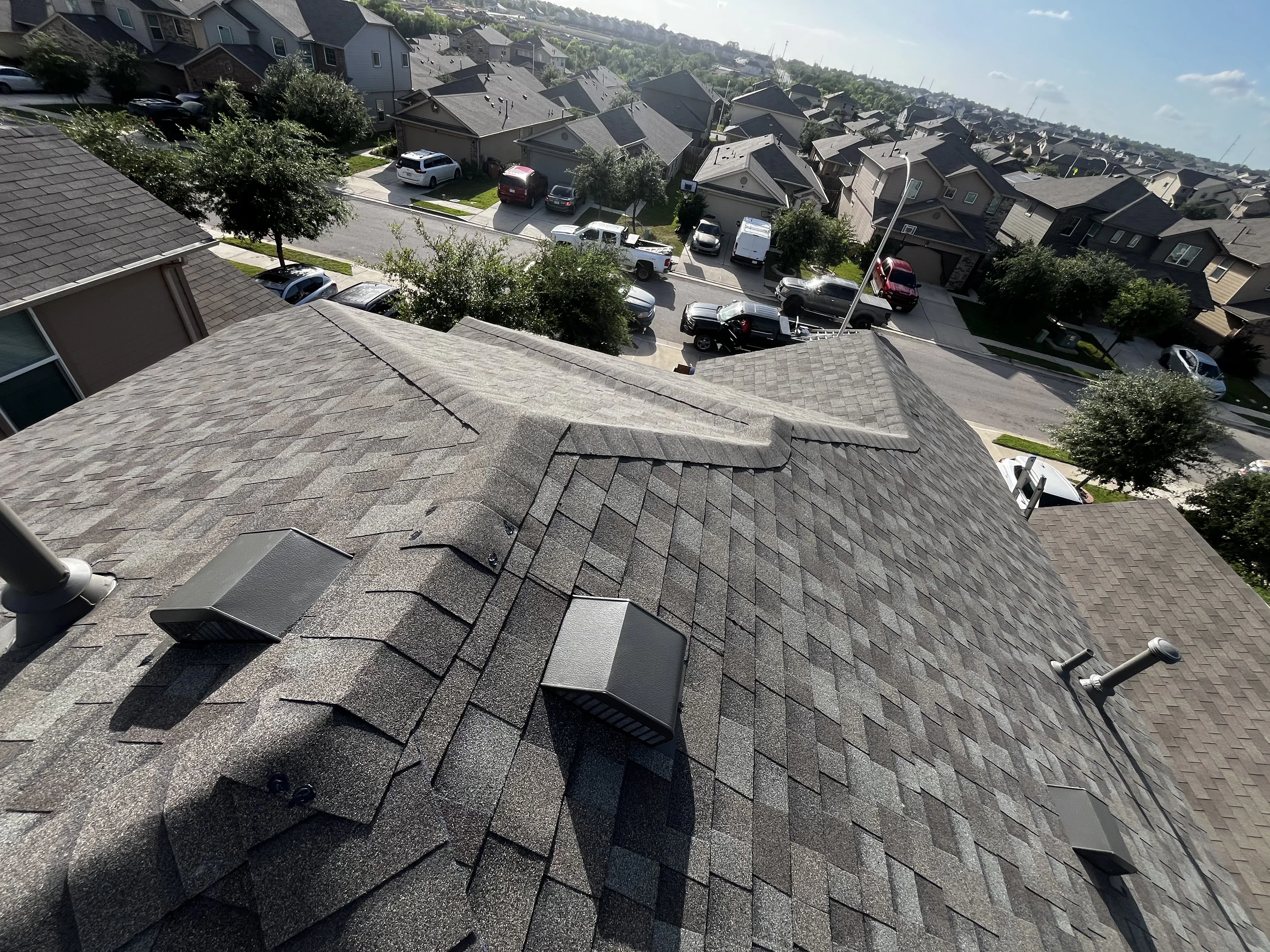 Aerial view of newly installed gray architectural shingles on residential roof with multiple planes and valleys