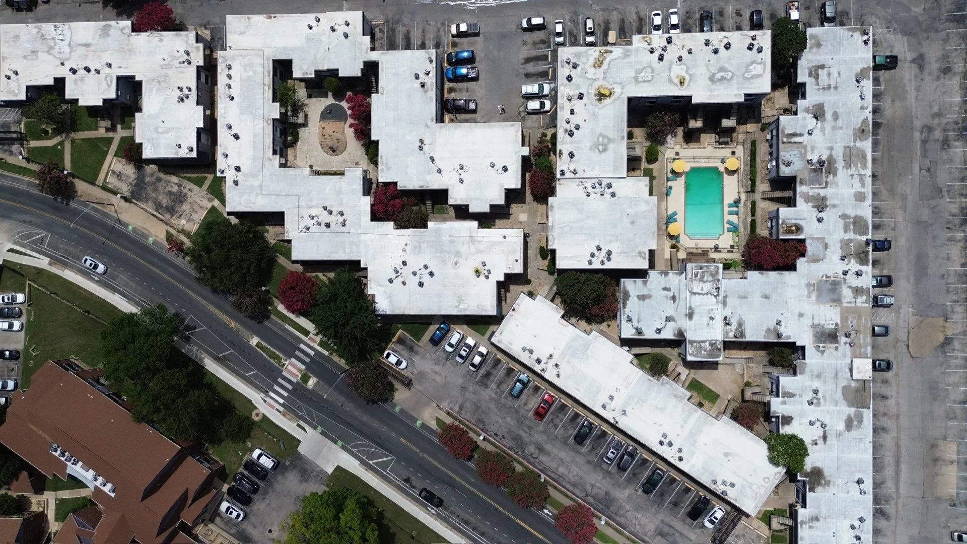 Aerial view of white membrane roofing installed on multiple connected commercial buildings with rooftop equipment