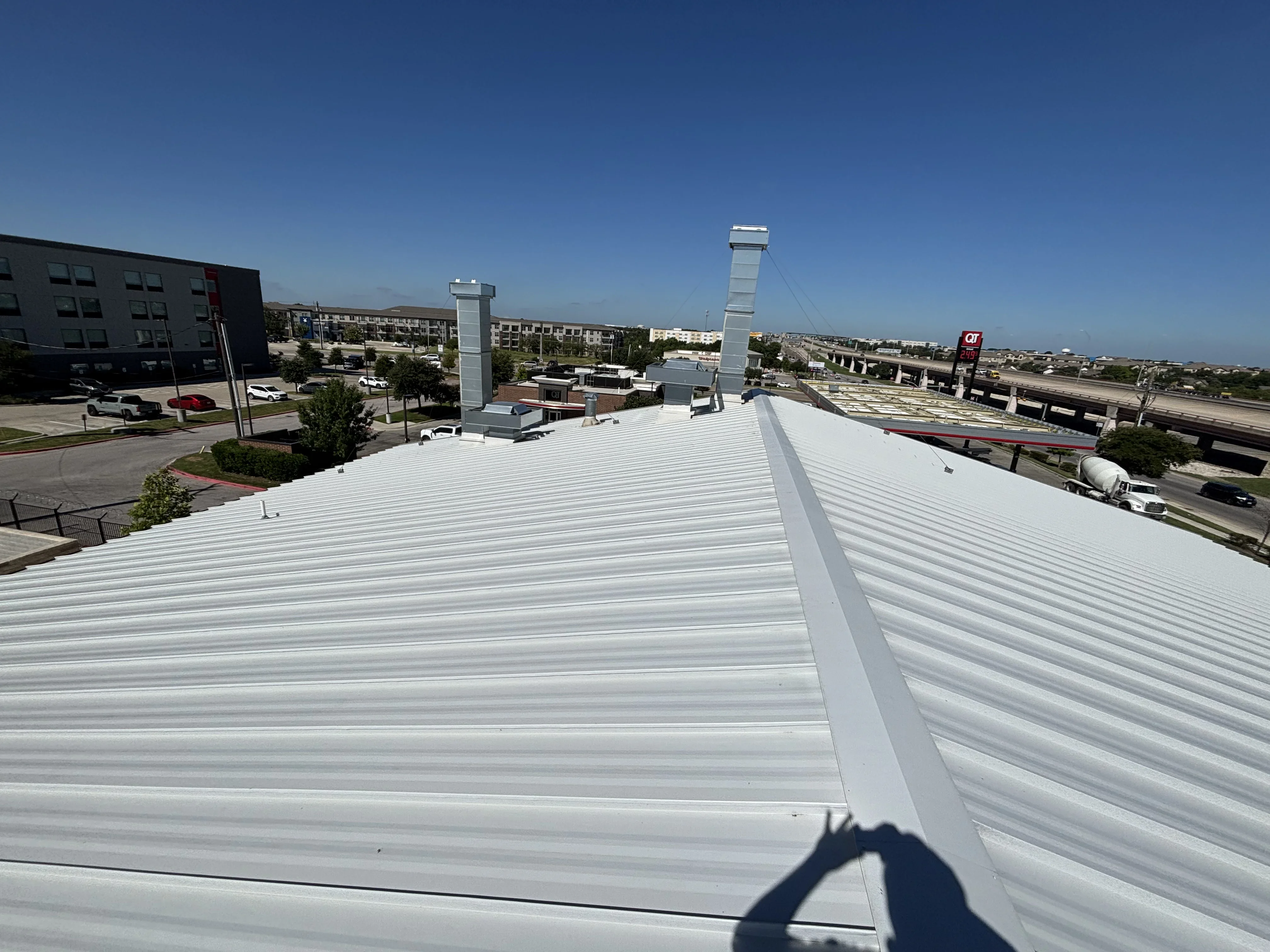 White standing seam metal roof installation with roof penetrations and HVAC equipment on commercial building