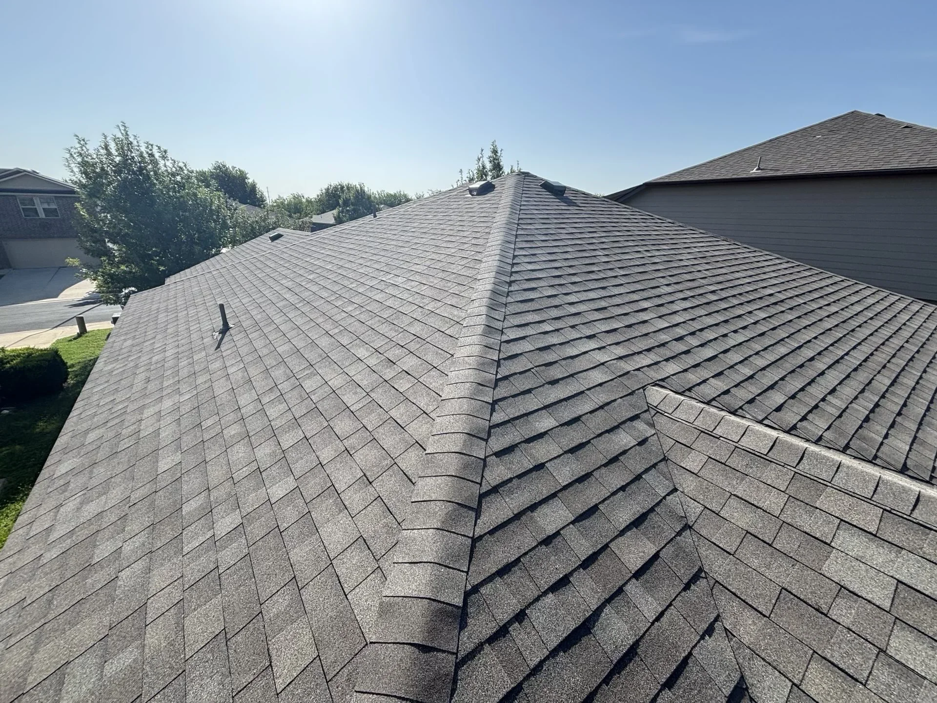 Charcoal gray architectural shingles installed on multi-pitched residential roof with clean ridge lines