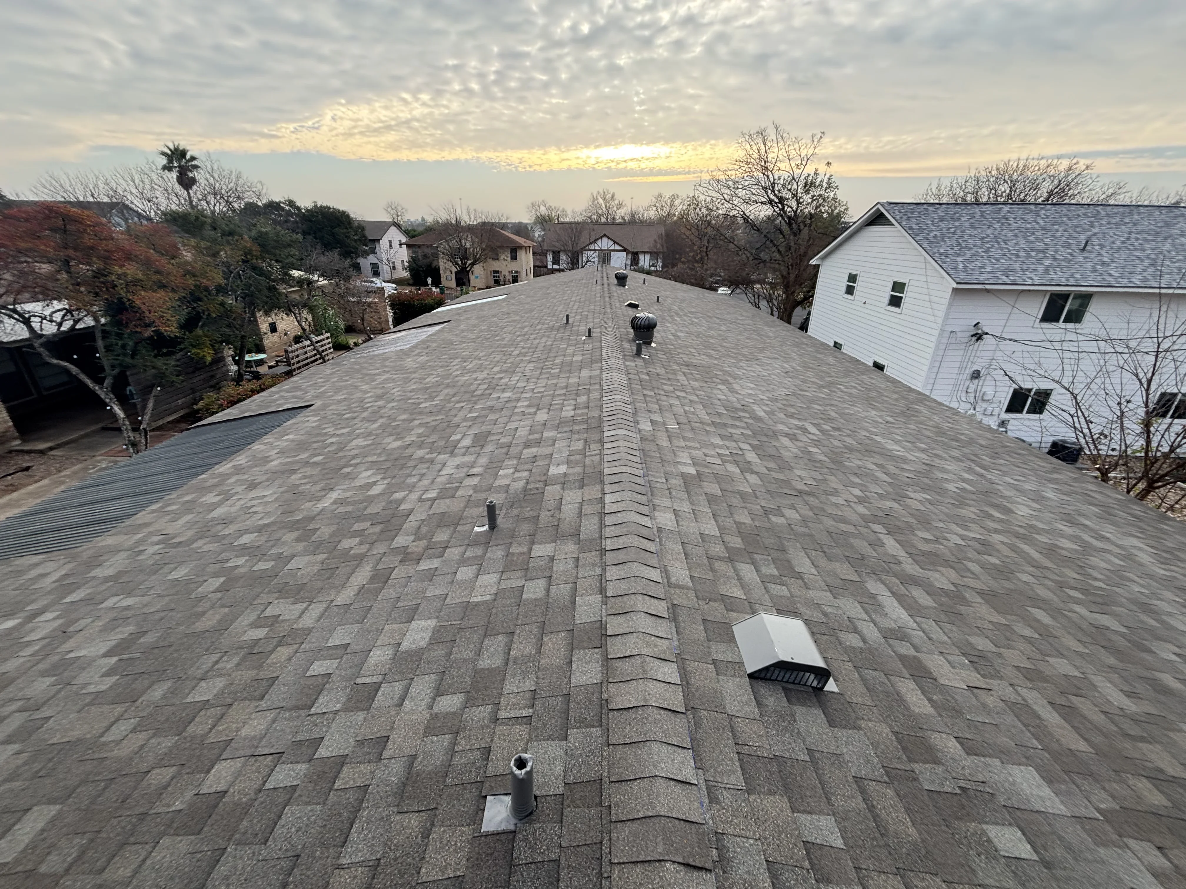 Gray architectural shingles installed in herringbone pattern with ridge line and roof vents